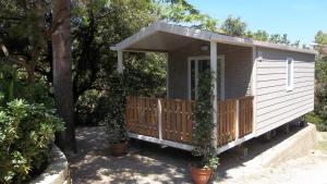 una pequeña casa con un porche con plantas. en Camping Village La Sorgente, en Portoferraio