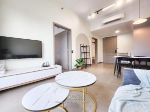 a living room with two tables and a flat screen tv at Mossaz at Empire Damansara by Wodages in Kuala Selangor