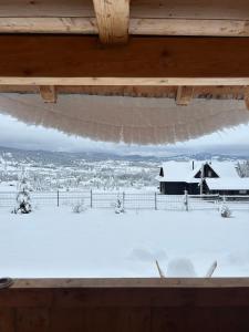 Blick auf ein schneebedecktes Feld aus dem Fenster in der Unterkunft Poiana cu Sinziene in Neagra Şarului