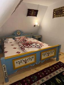 ein Schlafzimmer mit einem blauen Bett mit roten und weißen Kissen in der Unterkunft Poiana cu Sinziene in Neagra Şarului