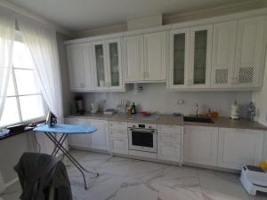 a kitchen with white cabinets and a table in it at Ziedulejas in Beika