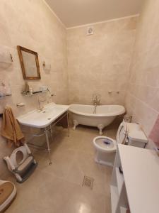 a bathroom with a tub and a sink and a toilet at Ziedulejas in Beika +11 photos