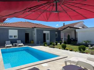 莫斯塔尔Vila Dolce Vita Mostar的游泳池和房子上的红伞