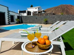Una mesa con un bol de naranjas y bebidas. en Villa Ocean Lanzarote, en Playa Blanca