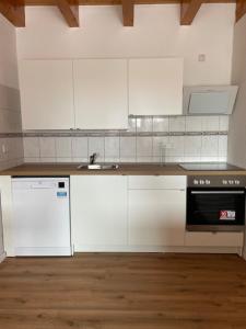 a kitchen with white cabinets and a sink and a stove at Ferienwohnung Sonnenschein in Kappel-Grafenhausen