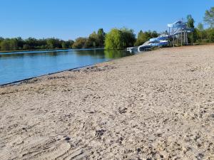 a sandy beach next to a river with boats at Lake Villa Castéra-Verduzan in Castéra-Verduzan