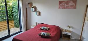 a bedroom with a red bed with two pillows on it at ANAHATA Appartement-Maison in Saint Paul de Vence