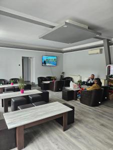 a living room with couches and tables and a tv at Hotel Hobby in Hunedoara