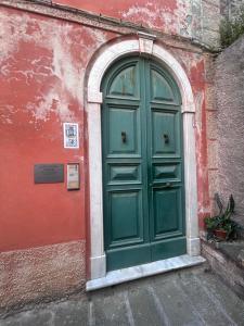 a green door in a red building with an arch at La Nicchia nel Carugio in Portovenere