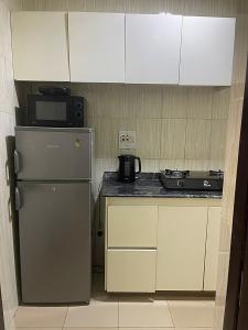 a small kitchen with a refrigerator and a microwave at Swazshortlet in Gwarinpa