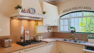 a kitchen with a stove and a sink and a window at Coastal Garden Paradise Retreat- 6 min from the beach in Charneca