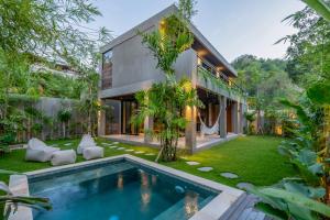 a house with a swimming pool in front of a yard at Aloha Villas - Modern villas with private pool and lush gardens in Kuta Lombok