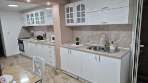 a kitchen with white cabinets and a sink at Apartmani Tiski Labud in Bečej
