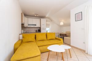 a living room with a yellow couch and a table at Apartment Majer in Mokošica