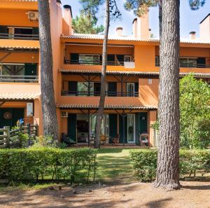 ein orangefarbenes Gebäude mit Bäumen davor in der Unterkunft Aroeira - Nature, Beach & Golf, by TimeCooler in Almada