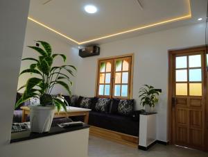 a living room with a black couch and two potted plants at Stay with dkouk in Akchour