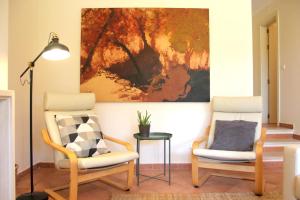 ein Wohnzimmer mit 2 Stühlen und einem Gemälde an der Wand in der Unterkunft Aroeira - Nature, Beach & Golf, by TimeCooler in Almada + 50 Fotos