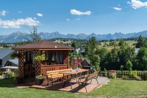 a wooden gazebo with a table and benches at Wierchowe Zacisze in Bukowina Tatrzańska