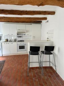 a kitchen with white cabinets and black chairs in it at Maison cœur de ville in Pertuis