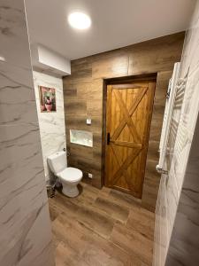 a bathroom with a toilet and a wooden door at Apartament przy sadzie in Szczytno