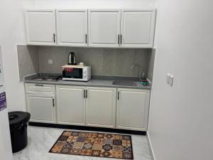 a kitchen with white cabinets and a microwave at شقق الدانة وصول ذاتي in Hafr Al Baten