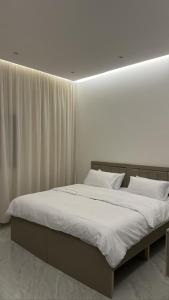 a bedroom with a large bed with white sheets at شقق الدانة وصول ذاتي in Hafr Al Baten