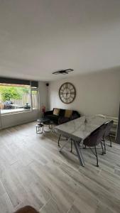 a living room with a table and a couch and a clock at A whole Family expat house with AC, garden, close to Efteling in Tilburg