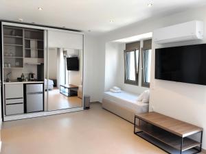 a white living room with a couch and a tv at Luminous Luxury Apartments in Limenas