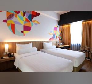 a hotel room with two beds and a painting on the wall at The Zuri Pekanbaru in Sultan Syarif Kasim II International Airport +4 photos