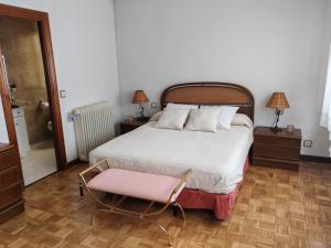 a bedroom with a large bed and a pink chair at Casa LuzValle in Arenas de San Pedro