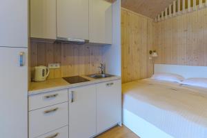 a kitchen with white cabinets and a bed in a room at Namelis Genio 7 in Palanga