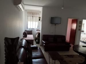 a living room with a leather couch and a table at Appartement de vacance à Tanmia Bloc 13 in Martil