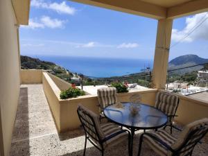 a patio with a table and chairs on a balcony at Panorama Georgia's house in Áyios Vasílios