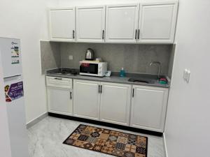 a kitchen with white cabinets and a microwave at شقق الدانة وصول ذاتي in Hafr Al Baten