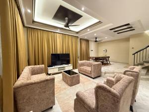 a living room with chairs and a flat screen tv at White House - Alor Setar in Alor Setar