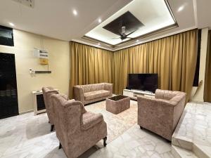 a living room with chairs and a flat screen tv at White House - Alor Setar in Alor Setar