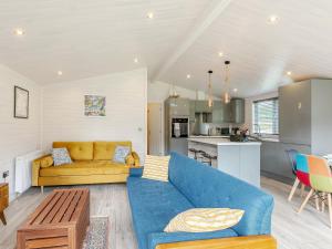 a living room with a blue couch and a kitchen at Erica Lodge in Willington