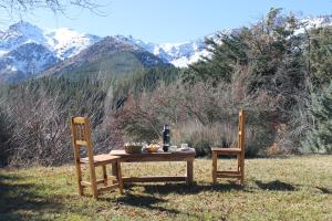 a table with a bottle of wine and two chairs at Cabaña Del Viento in Huinganco