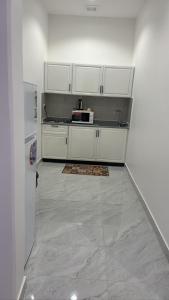 a kitchen with white cabinets and a white refrigerator at شقق الدانة وصول ذاتي in Hafr Al Baten