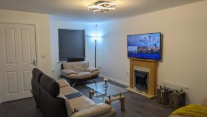 a living room with couches and a tv and a fireplace at Leyland Road Retreat - 4 Bedroom House in Burnley