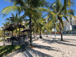 a beach with palm trees and benches on the sand at Origami Vinhomes Grand Park Q9 in Gò Công