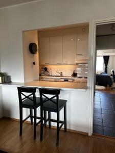 a kitchen with two black chairs and a counter at Lemmenpesä Ytimessä in Oulu