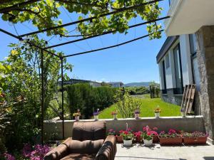 - une terrasse avec un canapé et des fleurs dans la cour dans l'établissement Вила Арапя, à Tsarévo