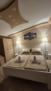 a bedroom with a large bed with two towels on it at Apartmani Tiski Labud in Bečej