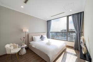a bedroom with a white bed and a large window at Origami Vinhomes Grand Park Q9 in Gò Công