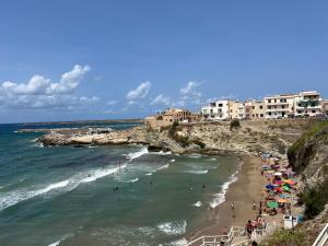 a beach with a bunch of people in the water at Appartamenti Tiffany & Timi in Carini