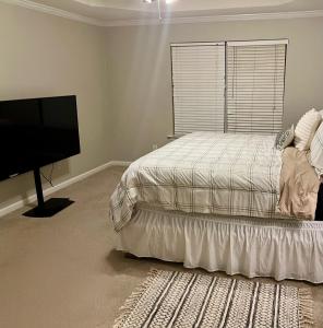 a bedroom with a bed and a flat screen tv at The Plush Retreat Marietta With Soaker Tub Walk In Closet in Marietta