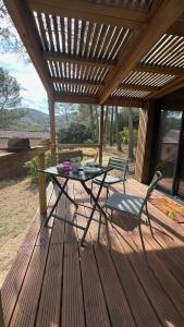 a table and a chair on a wooden deck at Bird in Provence - Cabane dans le Luberon in Cavaillon