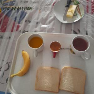 a tray with two cups of coffee and a banana at Chambres de charme en Normandie in Hauterive +7 photos