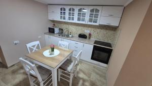 a kitchen with a table and chairs in a kitchen at Apartmani Tiski Labud in Bečej